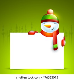 Cute smiling snowman holding blank board on fir trees decorated green background for Merry Christmas celebration.