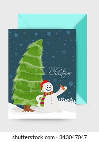 Cute snowman and Xmas Tree decorated greeting card with envelope for Merry Christmas celebration.