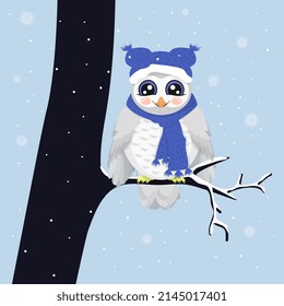 Cute snowy owl sits on a tree branch in winter