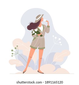 Cute stylish girl in a hat with a bouquet of flowers in her hand. Pretty young woman enjoying summer. Happy lady on a plant background. Happiness in the moment.