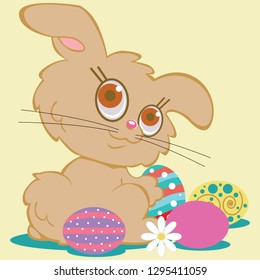 A cute tan bunny rabbit is surrounded by colorful decorated Easter eggs. Looking back over one shoulder with a satisfied expression and big brown eyes.