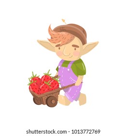 Cute troll boy character with wooden cart full of strawberries, funny creature cartoon vector Illustration