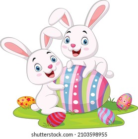 Cute two little bunnies with Easter egg in the grass