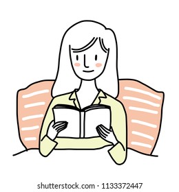 Cute woman in pajamas reading book on her bed comfortably. Book lover concept with young woman lying relax on bed and reading book. Woman lying on bed under comforter and focusing on book in hands.