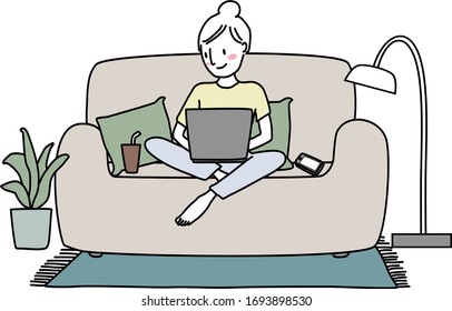 Cute woman sitting with legs crossed on couch and using laptop. Work From Home concept with young woman using computer on sofa. Woman sitting comfortably on couch, typing on laptop keyboard at home.