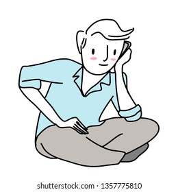 Un joven lindo sentado en el suelo con las piernas cruzadas, hablando por teléfono. Retrato de hombre feliz hablando por teléfono, sentado con piernas cruzadas en el suelo. Un tipo alegre escuchando la llamada.