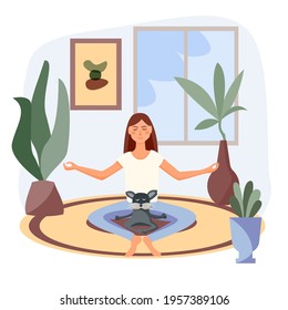cute young woman practices yoga with her cat. They sit together on the rug in living room and meditate.