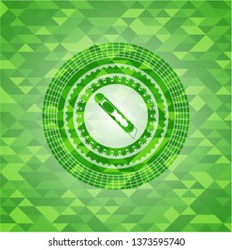 cutter icon inside green emblem with triangle mosaic background