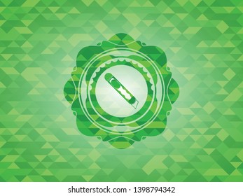 cutter icon inside green emblem with mosaic background