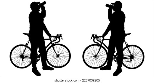 A cyclist in a cap with a bicycle holds a bicycle with one hand, holds a bottle of drink with the other hand, and drinks from it. Two people are standing opposite each other. Side view, profile.