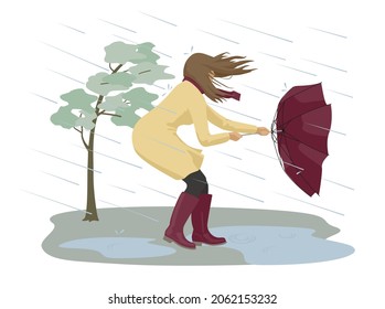 Dangerous condition with rain and wind. A woman tries to hold onto her umbrella during a strong storm. 