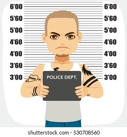 Dangerous male criminal with tattoos holding mugshot