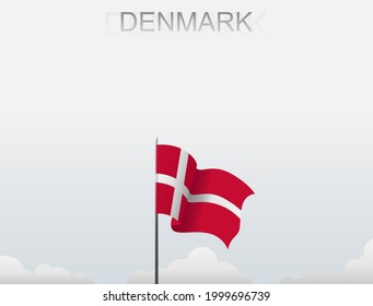 The Danish flag flutters on a pole standing tall under a white sky