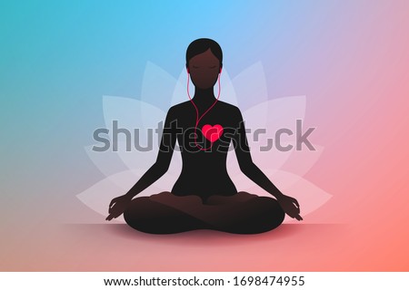 Dark silhouette of slender woman sitting in lotus position, listening music of her heart and meditating. Listen to your heart. Concept of harmony and tranquility in heart and thoughts