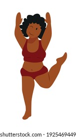 A dark skinned cheerful woman with black curly hair jumps on one leg with her hands up in a red top and underwear bodypositive