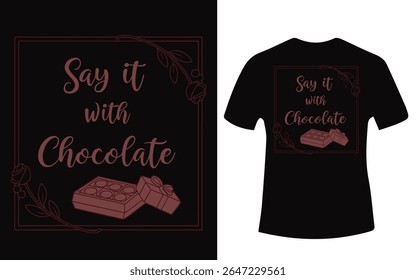 A dark t-shirt displays a design with chocolate boxes, floral accents, and the text "Say it with Chocolate."