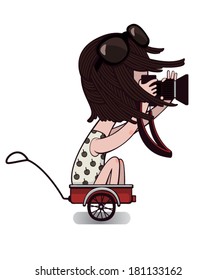 Dark-haired girl in a white dress with a camera in hand sits in the cart.