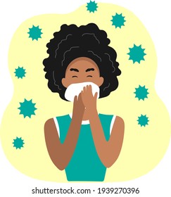 A dark-skinned woman with a cold sneezes into a handkerchief.