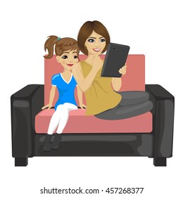 daughter and her mother with tablet computer sitting on a sofa