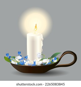 Decorative burning candle in a candlestick with the first spring blue and white flowers, an element of festive and wedding celebrations