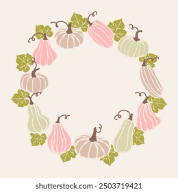A decorative circle of gently colored pumpkins and gourds surrounded by green leaves