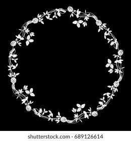 Decorative floral round frame with silhouettes of wild clover. White on black background.