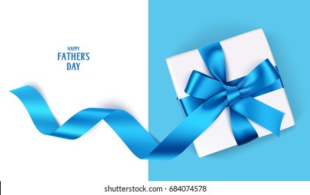 Decorative gift box with blue bow and long ribbon. Happy Father's Day text. Top view
