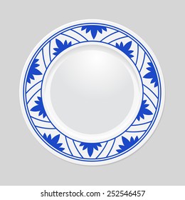 Decorative plate with patterned border, on gray background, top view.
