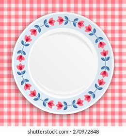 Decorative plate with patterned  floral border, on gingham tablecloth. Blank plate, top view. Vector illustration.