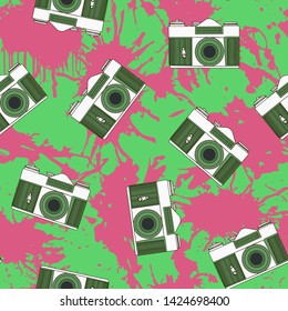 Decorative print with camera and pink paint splashes on green backdrop. Seamless pattern.