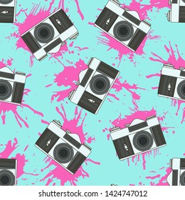 Decorative print with camera and pink paint splashes on blue backdrop. Seamless pattern.