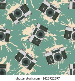 Decorative print with camera and yellow paint splashes on green backdrop. Seamless pattern.