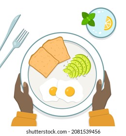 Delicioso desayuno de rebanadas de pan, huevos, aguacate en un plato. Vidrio de agua con limón y menta. Manos de una persona con la piel oscura sujetando el plato. Ilustración vectorial en estilo plano.