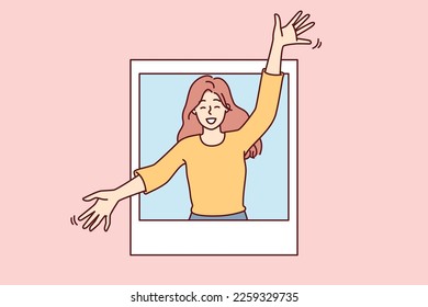 Delighted woman peeks out of photo with arms apart to hug you and give good mood. Attractive girl in casual clothes rejoices at meeting or wishes to hug goodbye