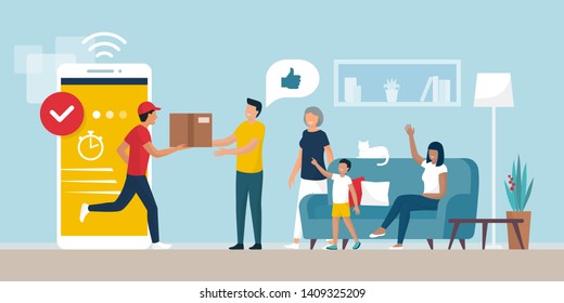 Delivery App Service: Man Delivering A Cardboard Box To A Happy Cheerful Family At Home In The Living Room, Logistics And Technology Concept