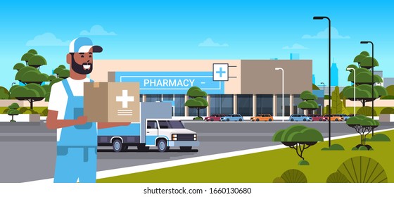 Deliveryman Carrying Medical Products In Cardboard Box With Cross Sign Modern Drugstore Front View Pharmacy Store Building Exterior Medicine Healthcare Delivery Service Concept Horizontal Portrait