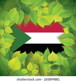 Dense, green leaves over the flag of Sudan