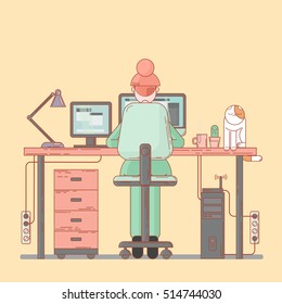 designer working behind two monitors next to the cat sitting