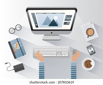 Designer working on computer at desk on grey background