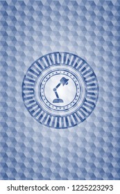 desk lamp icon inside blue emblem or badge with abstract geometric pattern background.