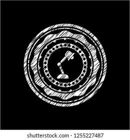 desk lamp icon inside chalkboard emblem on black board