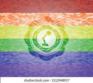 desk lamp icon inside emblem on mosaic background with the colors of the LGBT flag