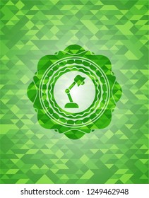 desk lamp icon inside green emblem. Mosaic background
