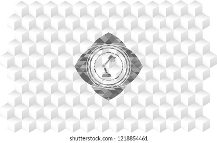 desk lamp icon inside grey badge with geometric cube white background