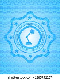 desk lamp icon inside light blue water wave style emblem.