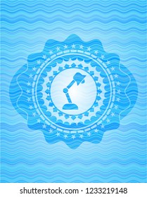 desk lamp icon inside sky blue water wave emblem background.