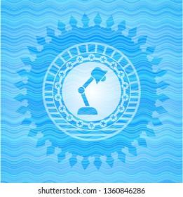 desk lamp icon inside sky blue water wave style badge.