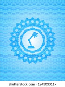 desk lamp icon inside water wave style emblem.