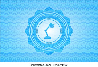 desk lamp icon inside water wave style emblem.