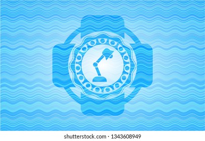 desk lamp icon inside water representation emblem.